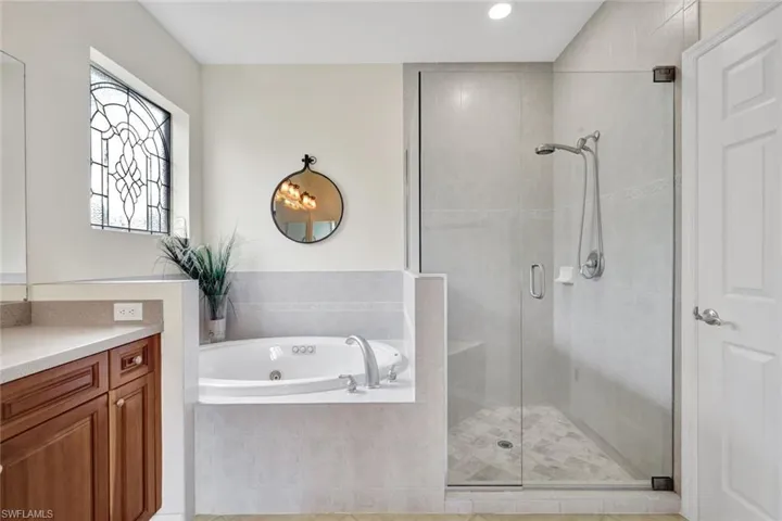 Bathroom with a shower stall, vanity, a whirlpool tub, and recessed lighting