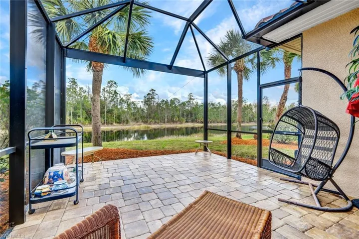 View of patio / terrace with a sunroom, a water view, a lanai, and view of scattered trees