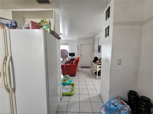 Kitchen with white fridge with ice dispenser and light tile patterned floors