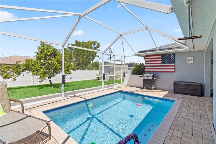 View of swimming pool with glass enclosure, a patio, a sunroom, grilling area, and a fenced backyard