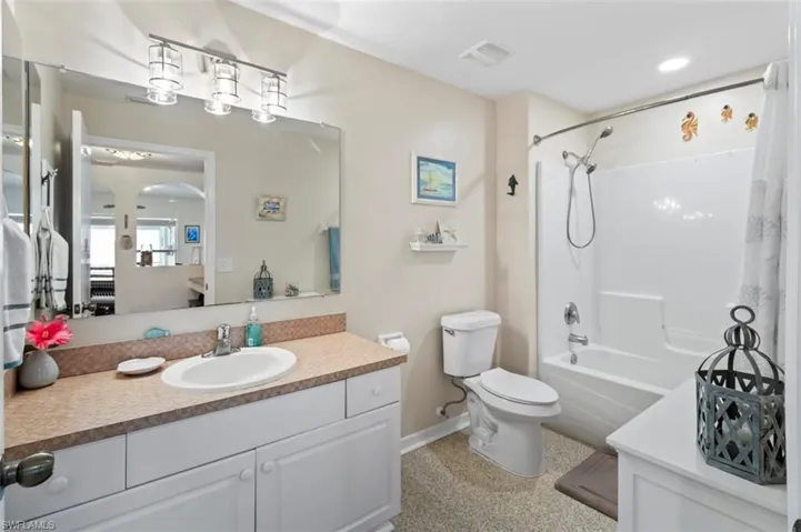 Bathroom featuring shower / bath combination with curtain, vanity, and recessed lighting