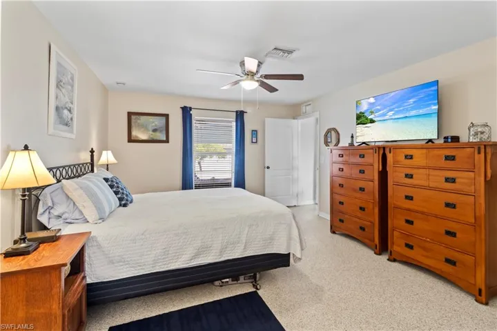 Bedroom with ceiling fan and light carpet