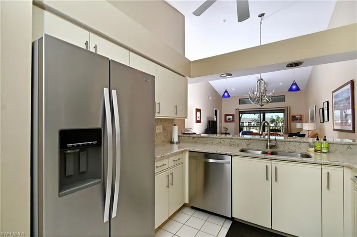 Kitchen with hanging light fixtures, sink, vaulted ceiling, appliances with stainless steel finishes, and tasteful backsplash