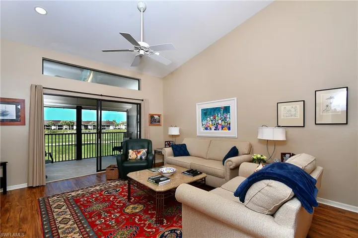 Living room with ceiling fan, high vaulted ceiling, and dark wood-type flooring