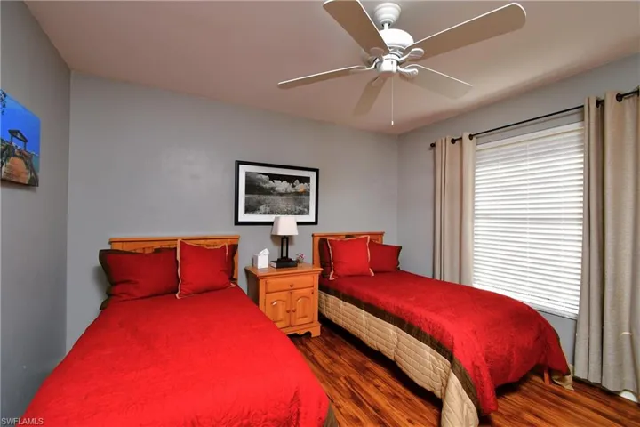 Bedroom with ceiling fan, dark hardwood / wood-style flooring, and multiple windows