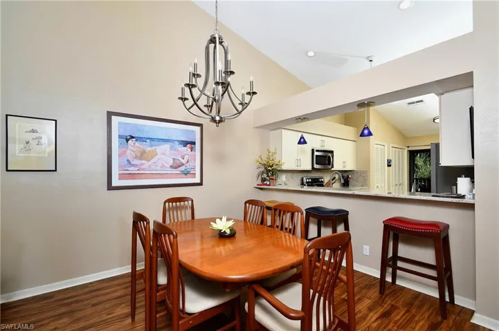 Dining room with a notable chandelier, sink, lofted ceiling, and dark wood-type flooring