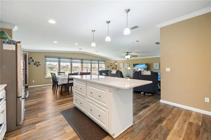 Kitchen featuring white cabinetry, freestanding refrigerator, open floor plan, vaulted ceiling, and light wood-style floors