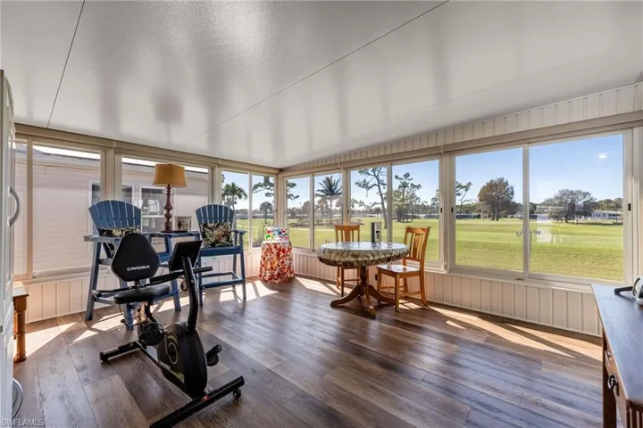 Sunroom / solarium with view of golf course and wood-type flooring