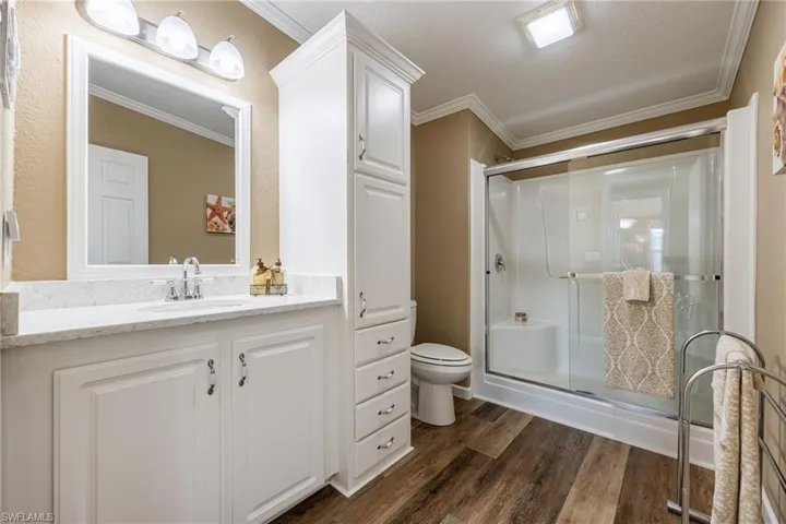 Bathroom with a shower stall, vanity, dark wood-style flooring, and ornamental molding