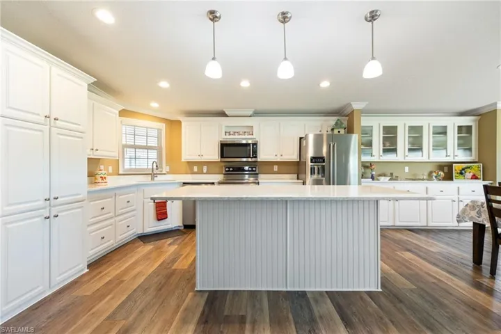 Kitchen featuring appliances with stainless steel finishes, dark wood-style flooring, white cabinetry, ornamental molding, and recessed lighting