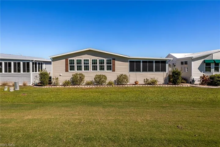 View of front of property featuring a sunroom and a front lawn