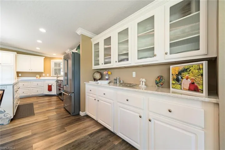 Kitchen featuring white cabinetry, appliances with stainless steel finishes, dark wood-style floors, crown molding, and recessed lighting