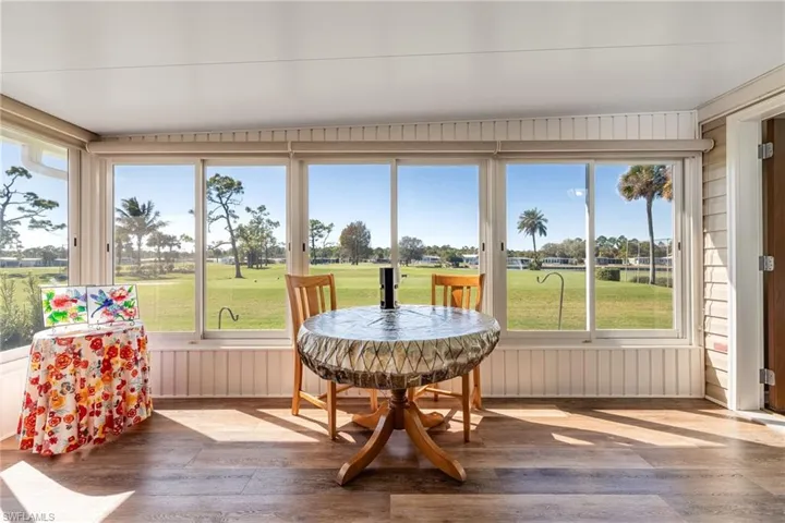 Sunroom / solarium with golf course view and hardwood / wood-style floors
