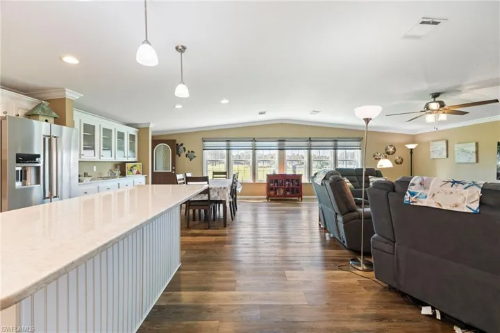 Living room with ornamental molding, vaulted ceiling, and dark wood-style flooring