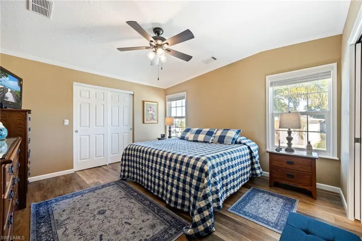 Bedroom featuring wood finished floors, a closet, ornamental molding, and a ceiling fan