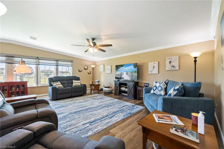 Living room with ornamental molding, wood finished floors, and ceiling fan