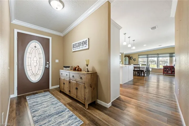 Foyer entrance with crown molding, dark wood-style flooring, a textured ceiling, and a textured wall