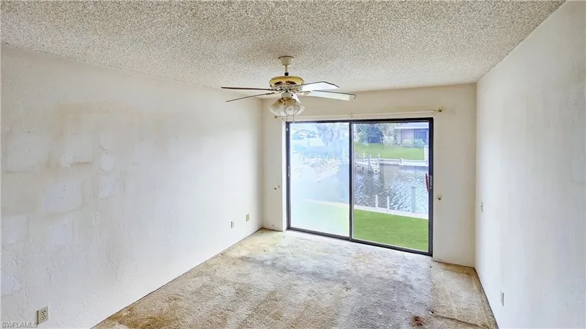 Carpeted empty room featuring ceiling fan, a wealth of natural light, and a textured ceiling