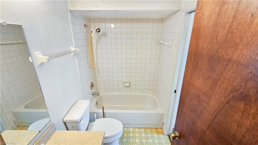 Bathroom with tiled shower / bath and toilet