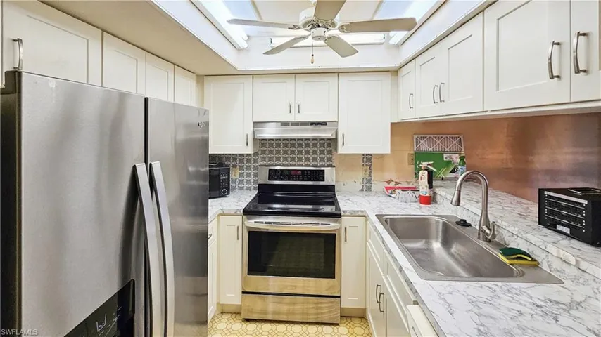 Kitchen featuring a skylight, sink, stainless steel appliances, and ceiling fan