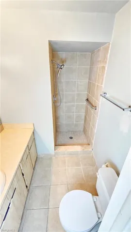 Bathroom featuring tiled shower, tile patterned flooring, toilet, and vanity