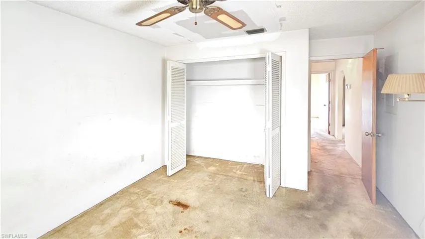 Unfurnished bedroom featuring light colored carpet, a textured ceiling, ceiling fan, and a closet