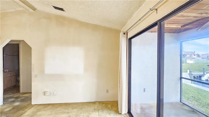 Spare room featuring light carpet, a wealth of natural light, and vaulted ceiling with beams