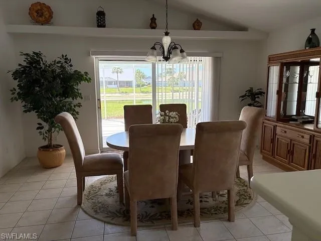 Dining room with lofted ceiling, suspended lighting, and light tile patterned floors