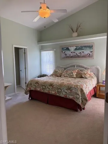 Bedroom featuring a ceiling fan, light colored carpet, and lofted ceiling