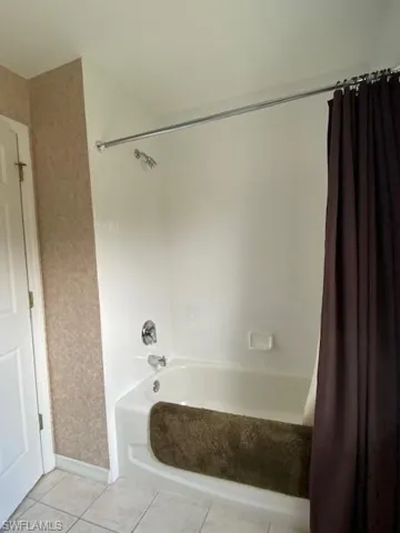 Full bathroom featuring light tile patterned floors and shower / bath combination with curtain