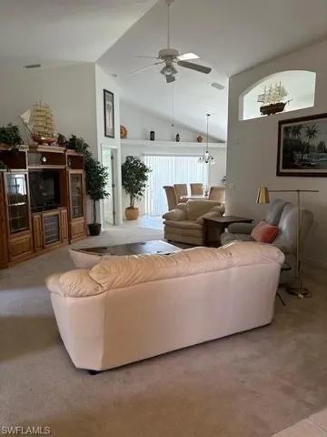 Living area with plenty of natural light, ceiling fan, light carpet, and a high ceiling