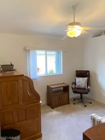 Den with light colored carpet and a ceiling fan