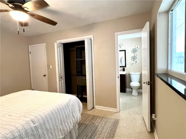 Primary Bedroom with baseboards, ensuite bathroom, a closet, and a ceiling fan