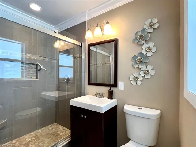 Primary Bathroom featuring toilet, crown molding, a shower stall, vanity, and plenty of natural light
