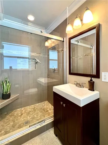 Primary Bathroom featuring a shower stall, crown molding, vanity, and speckle patterned floor