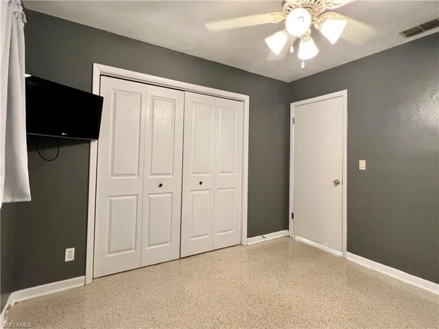 bedroom with baseboards, dark aggregate flooring, a closet, and a ceiling fan