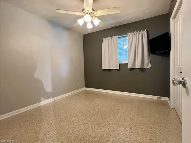 Spare room featuring baseboards, speckle patterned floor, and ceiling fan