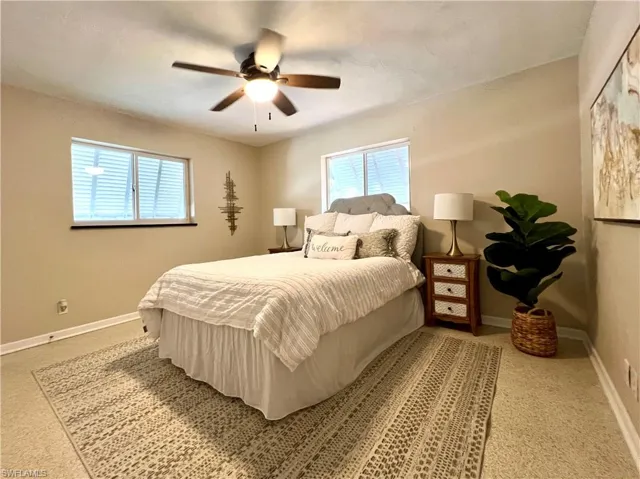 Primary Bedroom with multiple windows, baseboards, carpet floors, and ceiling fan