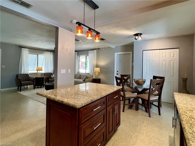 Kitchen featuring open floor plan, plenty of natural light, pendant lighting, and light stone counters
