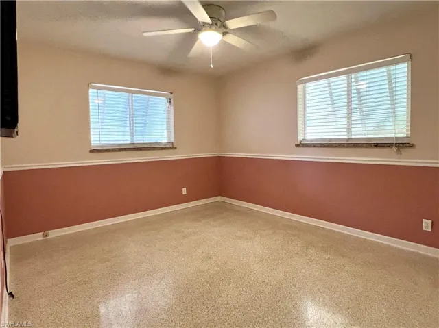 Unfurnished room featuring plenty of natural light, a ceiling fan, and baseboards