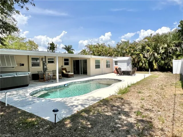 Back of property with a hot tub, a patio, an outdoor pool, stucco siding, and an outdoor hangout area