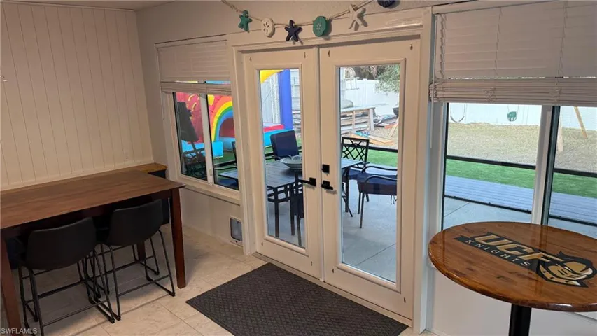 Doorway featuring french doors, tile patterned floors, and wooden walls