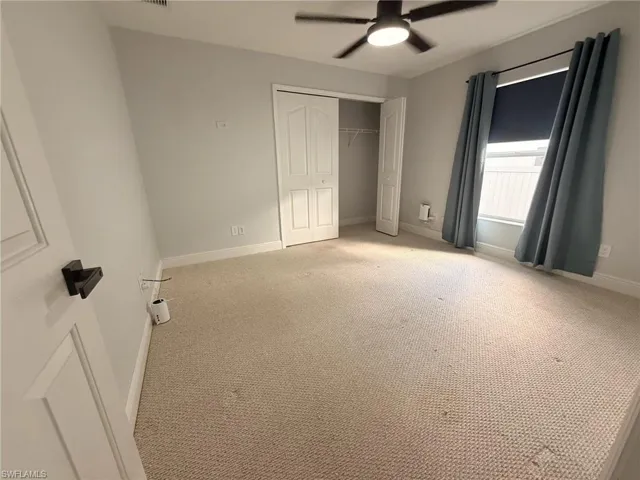 Unfurnished bedroom featuring light carpet, a closet, and a ceiling fan