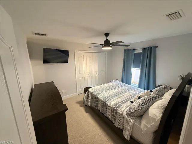 Carpeted bedroom featuring a ceiling fan and a closet