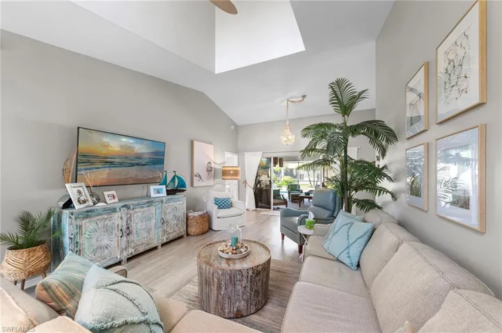 Vaulted ceilings with a skylight illuminate this living space featuring wood-finish flooring