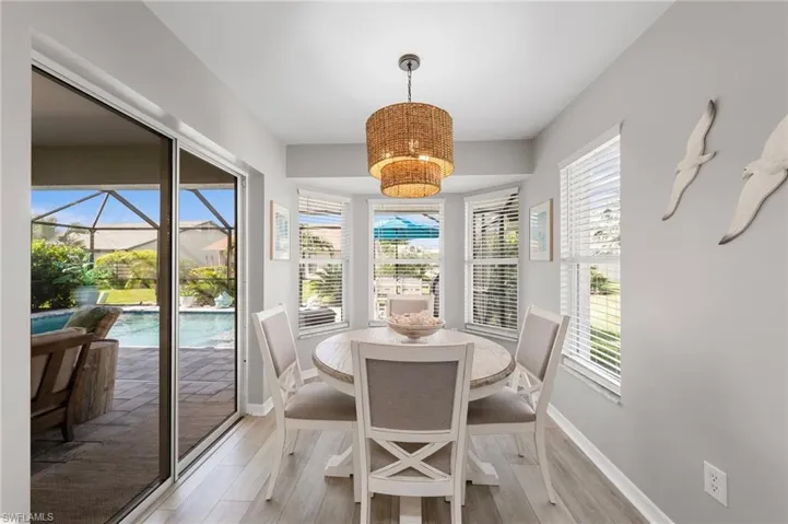 Dining area featuring wood-finish flooring, a contemporary rattan chandelier, and a bay window with multiple windows
