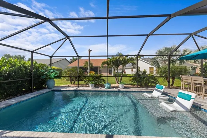 Screened pool enclosure featuring a beautiful saltwater pool with sun shelf for the ultimate relaxation