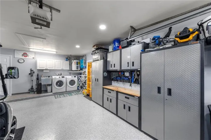 Spacious garage featuring epoxy flooring, white cabinetry and a utility sink