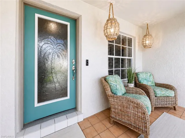Entryway featuring a turquoise door with frosted glass paneling, tile flooring, and white stucco walls