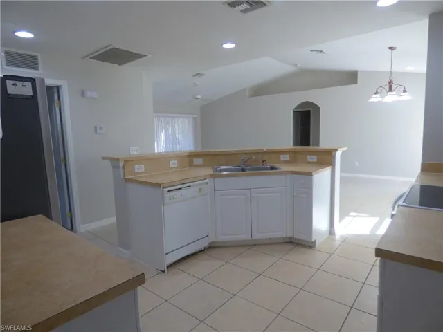 Kitchen with light tile patterned floors, white cabinets, a center island with twin sink, new faucet, light countertops, and dishwasher